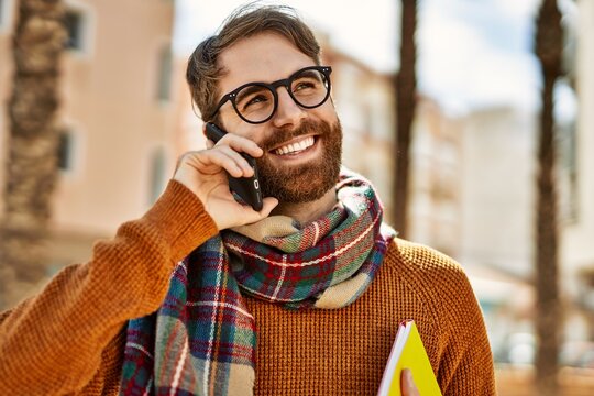Caucasian man with beard having a conversation speaking on the phone outdoors on a sunny day
