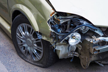 Fototapeta na wymiar Car after an accident close-up, headlamp is broken, front bumper is torn off, flat tire
