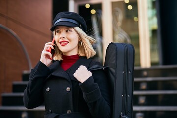 Young blonde musician woman talking on the smartphone at music academy.