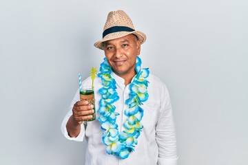 Middle age latin man wearing summer style drinking mojito glass looking positive and happy standing and smiling with a confident smile showing teeth