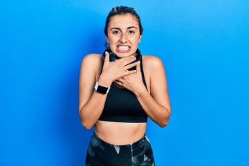 Fototapeta na wymiar Beautiful hispanic woman wearing gym clothes and using headphones shouting and suffocate because painful strangle. health problem. asphyxiate and suicide concept.
