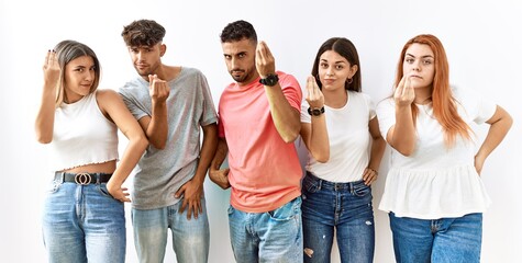 Group of young friends standing together over isolated background doing italian gesture with hand and fingers confident expression