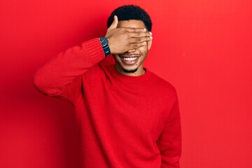 Young african american man wearing casual clothes and glasses smiling and laughing with hand on face covering eyes for surprise. blind concept.