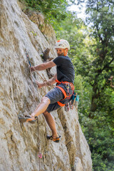 Athletic mid age man in a difficult rock climbing tour in the La Gola climbing area, Sarca Valley, Lake Garda mountains, Trentino Italy