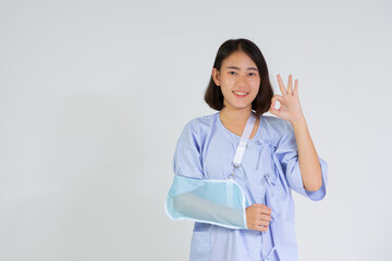 Broken arm girl in left arm sling thumbs up. Woman showing pain from health care, broken arm