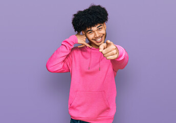 Young african american man with afro hair wearing casual pink sweatshirt smiling doing talking on...
