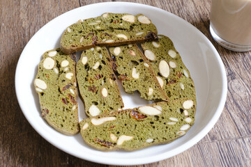 Homemade matcha biscotti cookies without sugar which are suitable for diet on wooden table with a glass of milk in the background