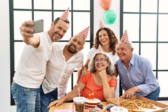 Group of middle age friends celebrate birthday make selfie by the smartphone at home.