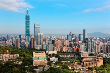 Obraz premium Aerial panorama of Downtown Taipei, vibrant capital city of Taiwan, with prominent Taipei 101 Tower among skyscrapers in Xinyi District & Yangmingshan Mountain on distant horizon under blue sunny sky
