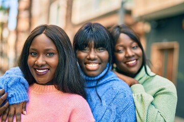 Three african american friends smiling happy hugging at the city.