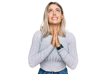 Beautiful blonde woman wearing casual clothes begging and praying with hands together with hope...