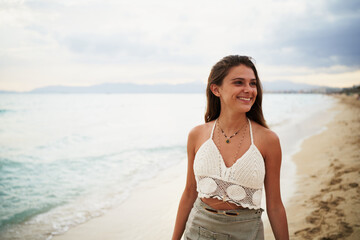 Fototapeta na wymiar Portrait of smiling young woman with sunglasses walking on beach