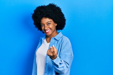 Fototapeta na wymiar Young african american woman wearing casual clothes beckoning come here gesture with hand inviting welcoming happy and smiling