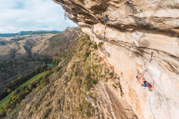 Aerial view of a rock climber holding on with one hand on rock