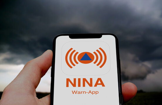 Logo der NINA Warn-App  wird auf einem Smartphone angezeigt, im Hintergrund ein aufziehendes Gewitter, Unwetter, Unwetterwarnung, Bev&ouml;lkerungsschutz, Warnsystem