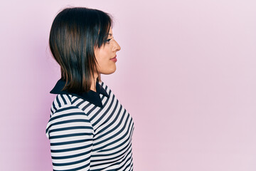 Young hispanic woman wearing casual clothes looking to side, relax profile pose with natural face with confident smile.