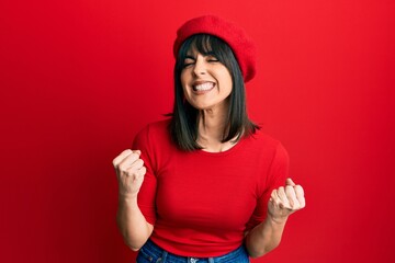 Young hispanic woman wearing french look with beret excited for success with arms raised and eyes closed celebrating victory smiling. winner concept.