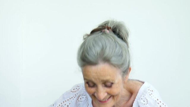 Beautiful old grandmother with grey hair and face with wrinkles is looking at the camera with smile on white background, mothers day, happy retirement