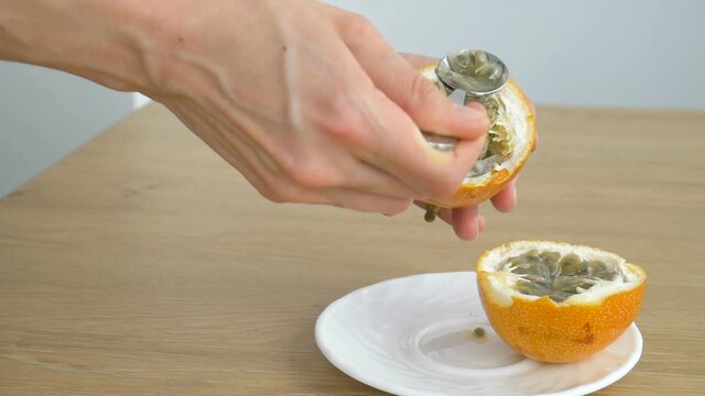 Female eats fresh organic ripe granadilla or yellow passion fruit with a spoon. Exotic fruits, healthy eating concept