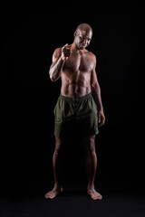 Black muscular man standing and pointing at camera with a confidence expression