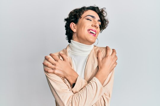 Young man wearing woman make up and woman clothes hugging oneself happy and positive, smiling confident. self love and self care