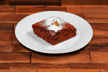 Ein leckeres Stück Schokokuchen mit Puderzucker auf einem weißen Teller