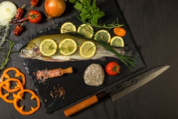 Raw trout on a black wooden table. Home preparation of trout.Healthy diet food. Fresh fish ready for grilling. Fishing industry.