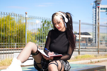 young and beautiful university girl with a punk tendency. she is sitting in the park. she has a...