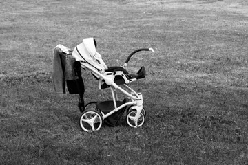 A white baby stroller on a summer glade, black and white