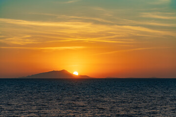 Naklejka na ściany i meble Beautiful sunset with sun hiding behind Ischia island over Tyrrhenian Sea