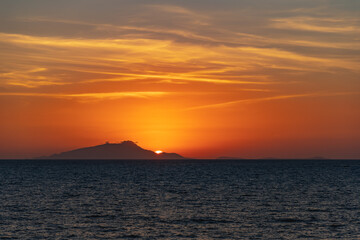 Beautiful sunset with sun hiding behind Ischia island over Tyrrhenian Sea