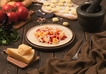 Italian dish, gnocchi with tomato sauce and basil, potato dumplings, on a wooden table, rustic, no people,
