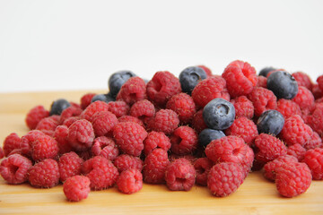 blueberries and raspberries on a white background. Useful vitamins berries in summer