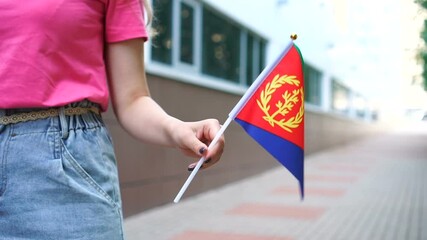 Unrecognizable woman holding Eritrean flag. Girl walking down street with national flag of Eritrea