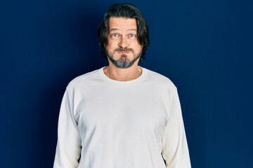 Middle age caucasian man wearing casual clothes puffing cheeks with funny face. mouth inflated with...