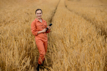 Fototapeta premium Woman caucasian technologist agronomist with tablet computer in the field of wheat checking quality and growth of crops for agriculture. Agriculture and harvesting concept.