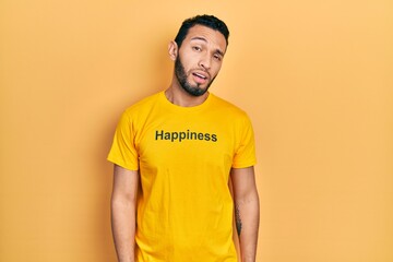 Hispanic man with beard wearing t shirt with happiness word message looking sleepy and tired, exhausted for fatigue and hangover, lazy eyes in the morning.