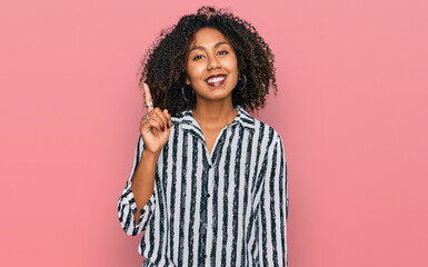 Young african american girl wearing casual clothes showing and pointing up with finger number one while smiling confident and happy.