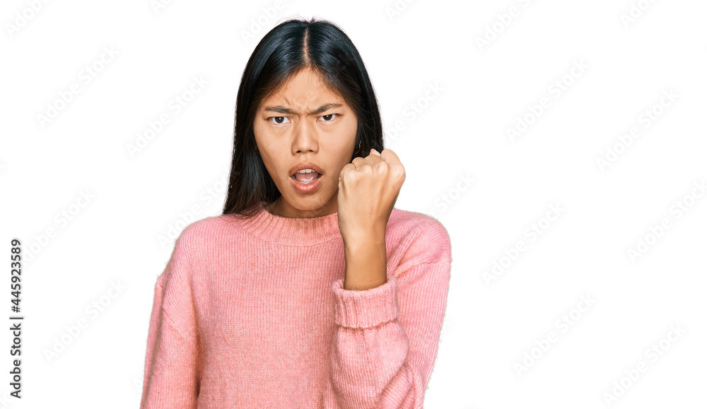 Poster beautiful young asian woman wearing casual winter sweater angry and mad raising fist frustrated and 