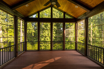 Modern new screened porch with plastic windows and composite floor with summer woods in the...