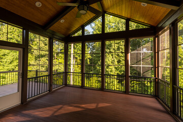 Fototapeta na wymiar Modern new screened porch with plastic windows and composite floor with summer woods in the background.