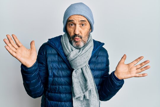 Middle age hispanic man wearing winter style clueless and confused with open arms, no idea and doubtful face.