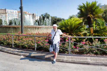 Fototapeta na wymiar Mature man in baseball cap on the background of the flowers and fountain
