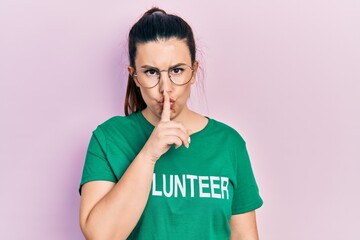 Young hispanic woman wearing volunteer t shirt asking to be quiet with finger on lips. silence and secret concept.
