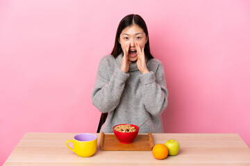 Young Chinese girl  having breakfast in a table shouting and announcing something