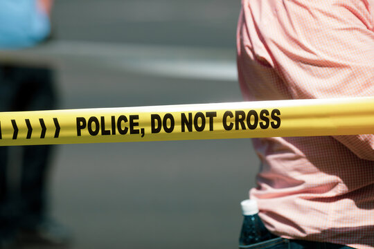 Shallow depth of field (selective focus) image with Police plastic tape reading Police, Do not cross, at a crime scene.