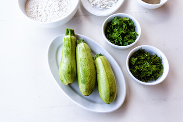 Baby zucchini on a white plate background. over white wooden table.  Organic food.
