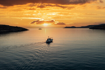 Fishing boat at sunset. Greece. Aerial drone view of typical fishing boat moving on calm sea and...