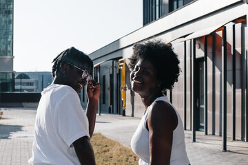 two happy African-American women are walking down the street in the summer