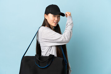 Young sport Chinese  woman with sport bag over isolated blue background doing strong gesture
